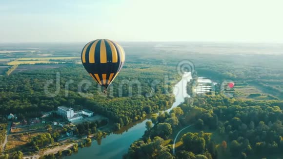 一个热气球的鸟瞰图飞过沿河的树木美妙的夏日日落景色视频的预览图