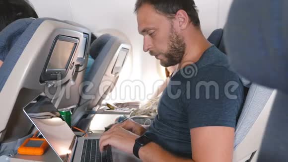 年轻专注的创意商人与智能手表在线工作在笔记本电脑移动办公室在飞机旅行视频的预览图