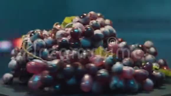 一串成熟的红葡萄和水滴在房间里旋转光线昏暗视频的预览图