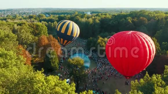 空中观看红色热气球在公园的树木中起飞美丽的天空和日落视频的预览图