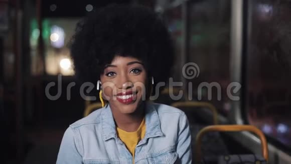 非裔美国妇女看着相机微笑着坐在公共交通工具斯特迪卡姆拍摄特写镜头城市视频的预览图