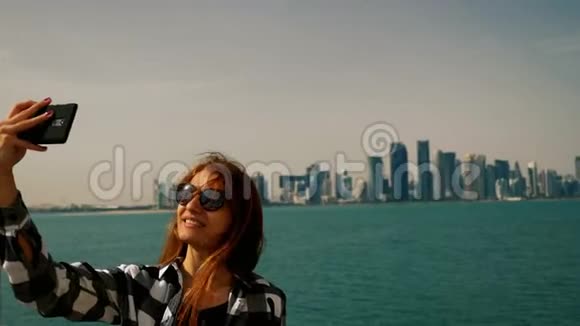 在多哈的摩天大楼里用智能手机拍照的旅游女孩视频的预览图