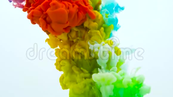 五颜六色的彩虹油漆从底部混合在水中墨水在水下旋转在白色上分离出的丝质墨水云视频的预览图