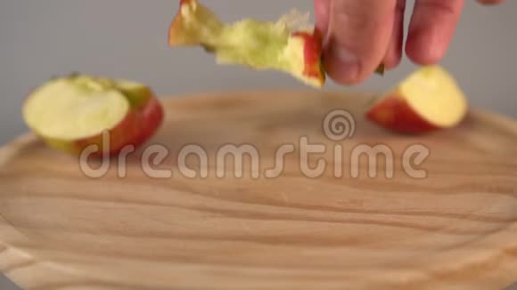 一只手用苹果片把苹果芯放在木表面视频的预览图