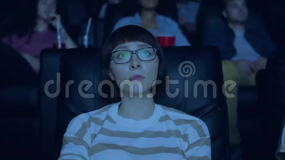 敏感的年轻女子愁眉苦脸地在电影院看有趣的戏剧视频的预览图