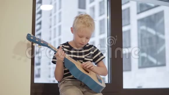 一个带着吉他的悲伤男孩坐在窗边视频的预览图