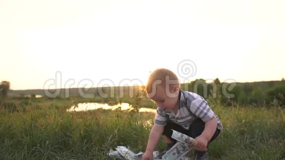 快乐男孩从草地上筹集资金缓慢地扔出美元钞票视频的预览图