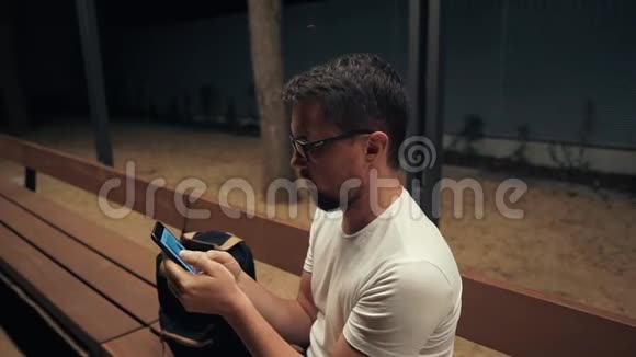 成年人正在用手机看照片晚上独自坐在户外视频的预览图