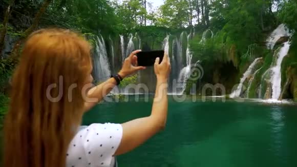 在森林瀑布拍照的旅游女孩视频的预览图
