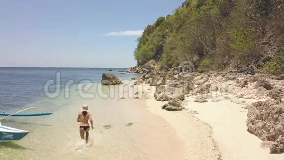 穿比基尼的女游客正在岛上的沙滩上奔跑后景视频的预览图