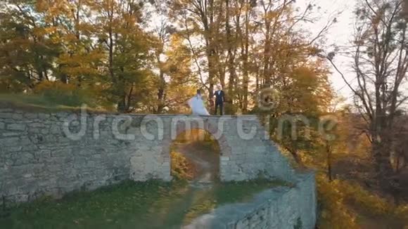 新婚夫妇可爱的新郎和新娘住在森林里一座被摧毁的建筑物的遗骸上幸福家庭视频的预览图
