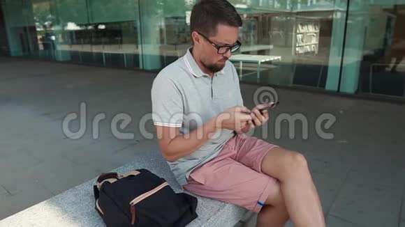 中年男子在现代手机屏幕上滑动坐在街上视频的预览图