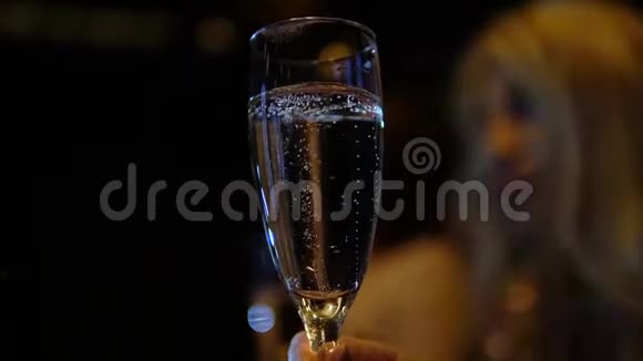 在俱乐部里和朋友一起喝香槟的女孩前景上有气泡的泡沫玻璃视频的预览图