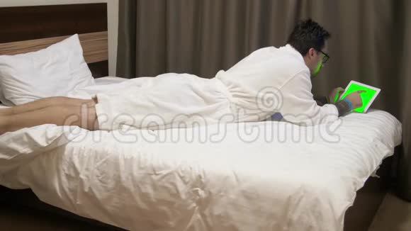 看数字平板电脑数据的人酒店里的人躺在床上使用触摸板视频的预览图