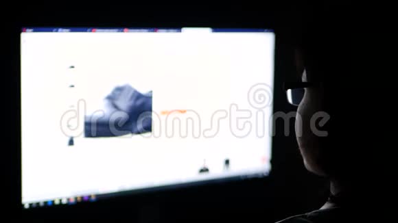 戴眼镜的黑发女人晚上使用电脑在家里通过网店浏览网上购物视频的预览图