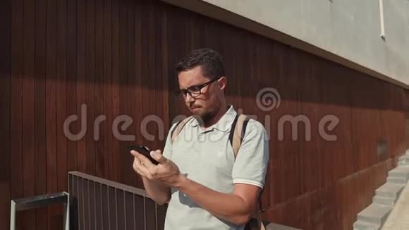 独自一个黑头发的男人正在户外敲打手机的触摸屏视频的预览图