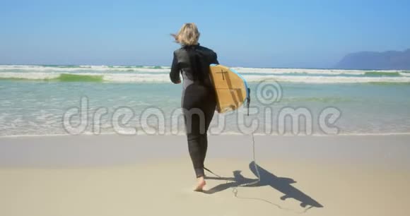 活跃的高白种人女性冲浪者在阳光下在海上奔跑的后视图视频的预览图