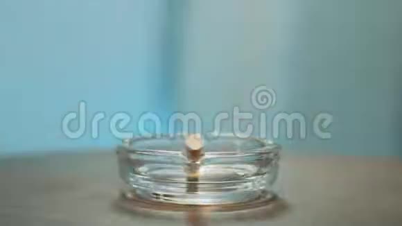 旋转工艺的时尚玻璃烟灰缸与燃烧的香烟放置在里面视频的预览图