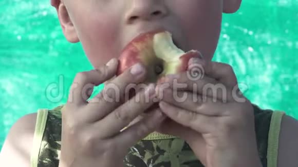 一个小男孩吃着美味苹果的特写镜头视频的预览图