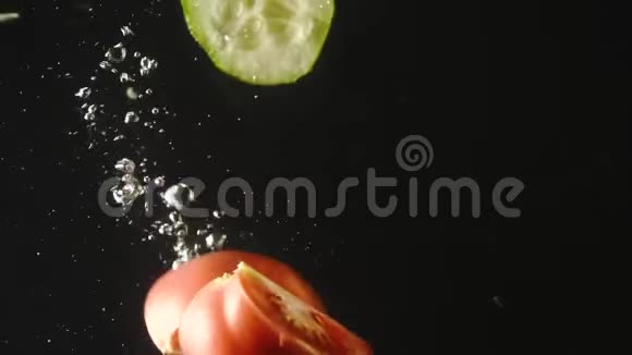 黄瓜和番茄片溅在水中的黑色背景水中的新鲜蔬菜接近有机有机视频的预览图
