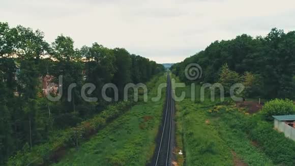 鸟瞰图向上移动聚焦在铁路轨道上在绿色森林的背景下展现出奇妙的乡村地区视频的预览图