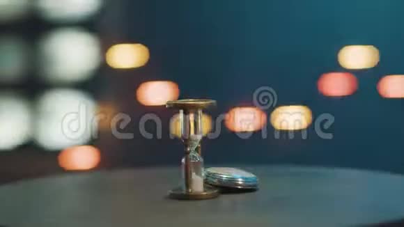 孤立的手表和沙漏放在房间里的深色圆形桌子上视频的预览图