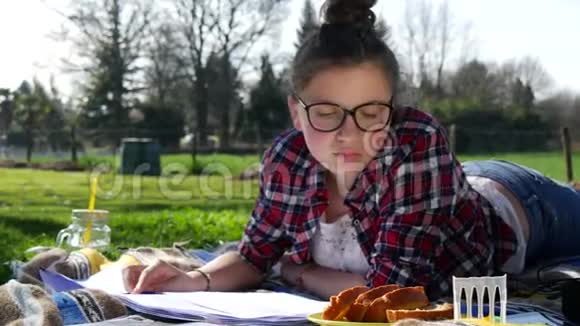 躺在草地上做作业和吃蛋糕的少女视频的预览图