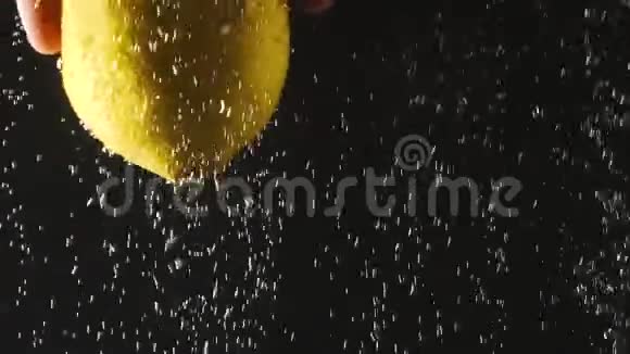 人的手拿着新鲜柠檬在水的黑色背景下柠檬在水中有气泡有机食品健康视频的预览图