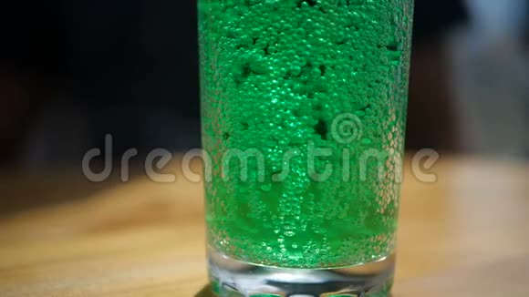 慢动作地站在桌子上的玻璃杯里溅起了气泡的绿可乐视频的预览图