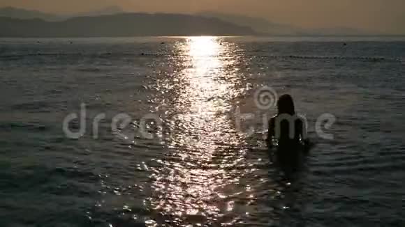 美丽的女孩穿着黑色泳衣在日出时从海里出来视频的预览图