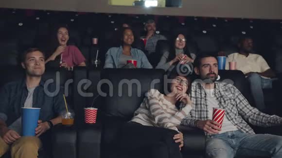 快乐的年轻人在电影院里看电影笑着玩视频的预览图
