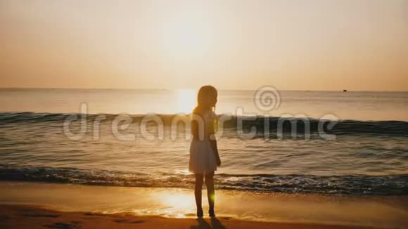 在令人难以置信的金色海洋日落海滩快乐的小女孩观看海浪来袭的电影后景拍摄视频的预览图