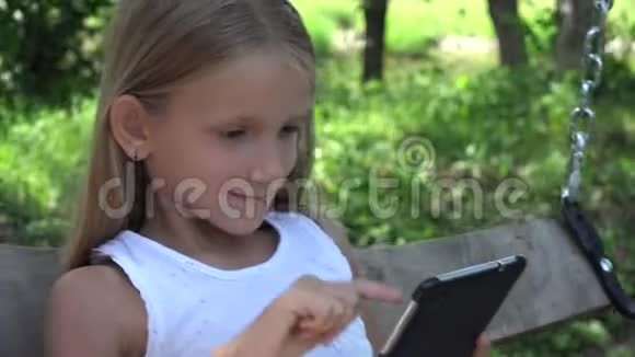 儿童在花园户外玩平板电脑女孩在院子里荡秋千夏景4K视频的预览图