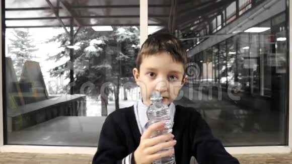 一个小学生坐在桌子旁嚼着塑料瓶里的水喝着视频的预览图