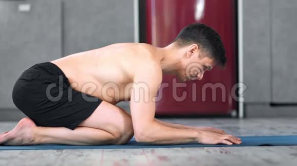 放松的健身男性练习瑜伽伸展放松在垫子室内全镜头视频的预览图