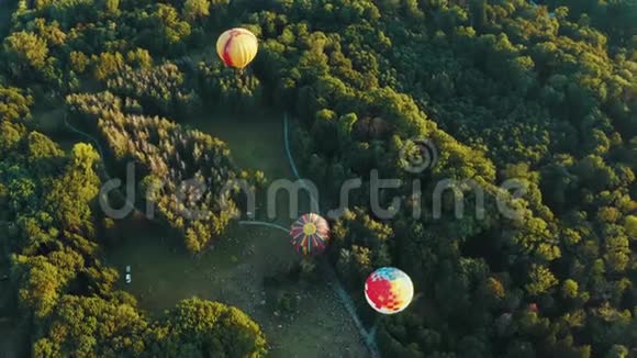 三个热气球的鸟瞰在公园的树木中起飞美丽的天空和日落视频的预览图