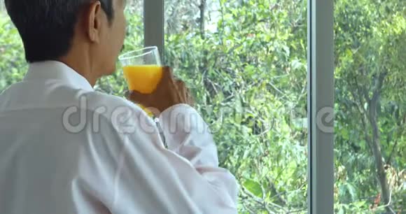 站着的亚洲老人喝着橙汁视频的预览图