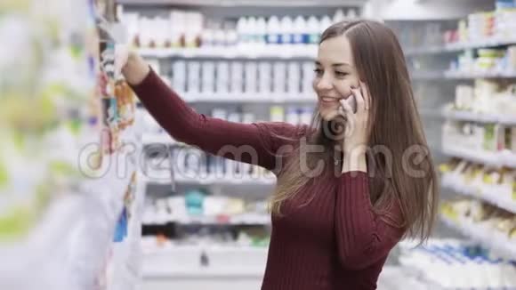 漂亮的女孩微笑着打电话在超市购物视频的预览图