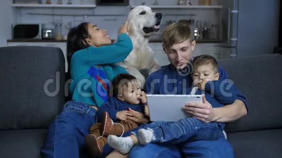 一家人在沙发上放松时女人抚摸狗视频的预览图