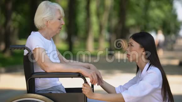 支持坐轮椅的悲伤老年妇女的女志愿者视频的预览图