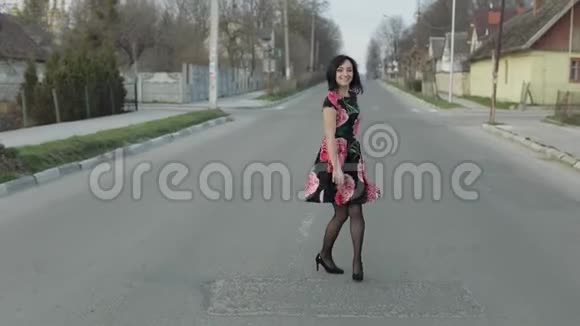 漂亮的年轻女子穿着一件连衣裙花在公路上奔跑视频的预览图