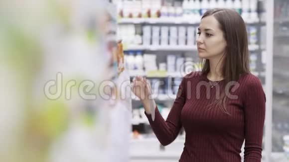 超市里的女人从货架上拿产品看标签然后把它放回原处视频的预览图