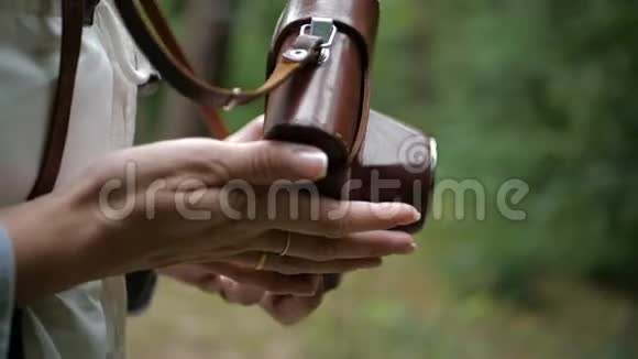 年轻的雌性手在松树林里玩棕色相机视频的预览图