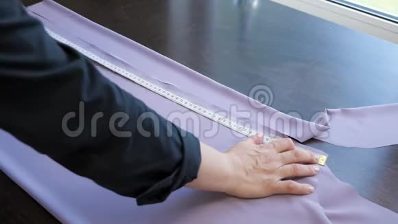 裁缝用布做图案来缝制衣服用胶带在桌子上测量视频的预览图