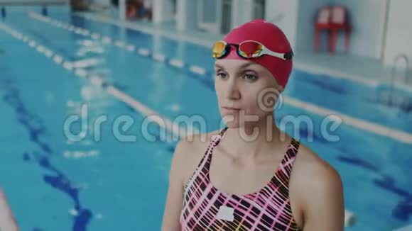漂亮的女游泳运动员戴着护目镜在水下漂浮她穿着泳衣和红色泳帽视频的预览图
