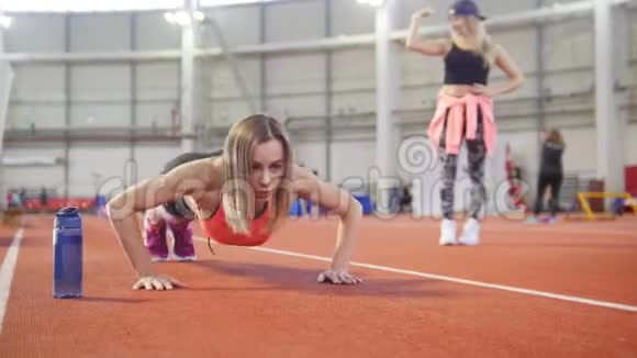 穿着运动服做俯卧撑的运动女性她身边有一瓶水视频的预览图