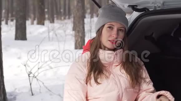 阳光明媚的冬日女孩坐在车里为相机摆出甜美的姿势视频的预览图