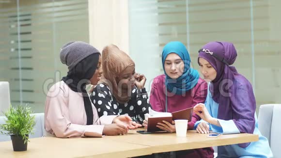 快乐的穆斯林多民族女孩在图书馆讨论书籍视频的预览图