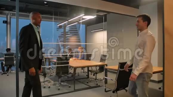 两位企业家在现代办公室的室内握手美洲人和高加索人的同事视频的预览图
