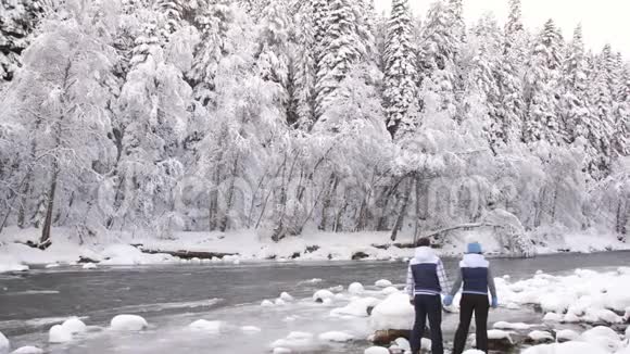 幸福夫妇站在山冬河上眺望远方冬季景观视频的预览图
